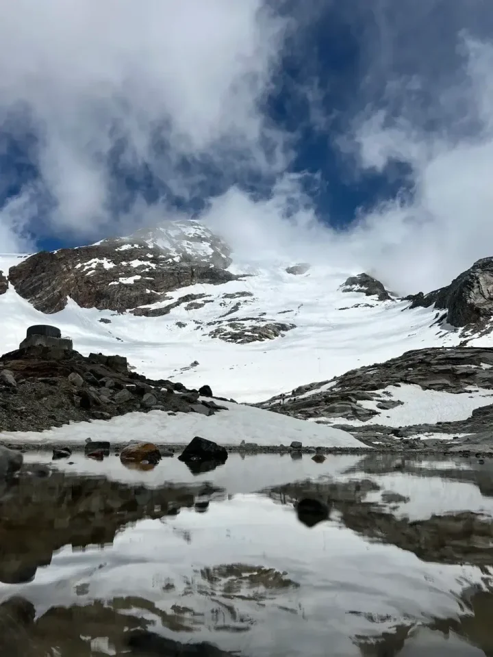 Vette innevate che si specchiano in un laghetto di montagna